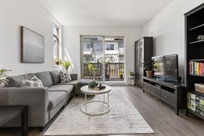 Surrey townhouse for rent - A living room with a grey couch, a white coffee table, and a black bookshelf.