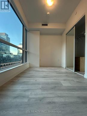 Toronto (Waterfront Communities) condo for rent - A spacious room with a view of the cityscape through large windows.
