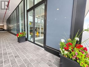 Oakville (Ro River Oaks) condo for rent - A building entrance with glass doors and a planter box with flowers.