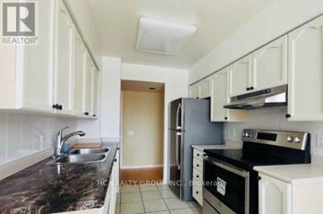 Toronto (Willowdale East) condo for rent - A kitchen with white cabinets and black countertops.