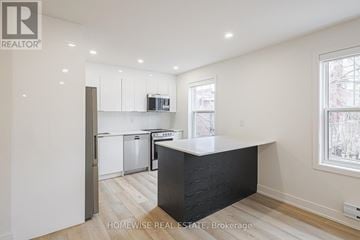 Toronto (Casa Loma) apartment for rent - A kitchen with white cabinets and a black island.
