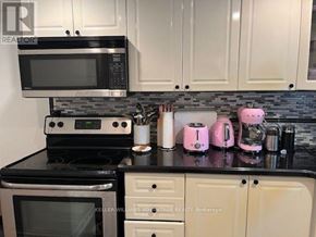 Toronto (Greenwood-Coxwell) apartment for rent - A kitchen with a black countertop and white cabinets.