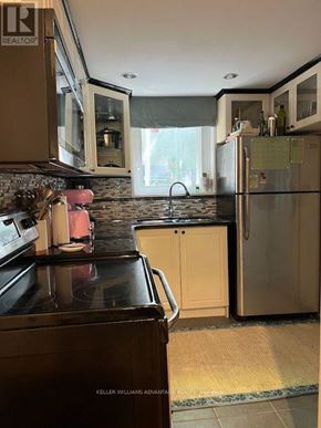 Toronto (Greenwood-Coxwell) apartment for rent - A kitchen with a black stove top and a refrigerator.