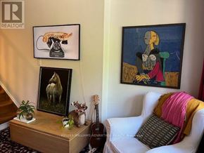 Toronto (Greenwood-Coxwell) apartment for rent - A living room with a guitar, a painting, a couch and a table with a plant and a picture of a horse.