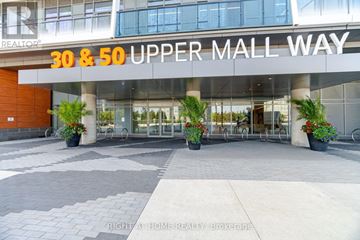 Vaughan (Brownridge) condo for rent - The entrance to the 30 & 50 Upper Mall Way building with a glass door and a plant on the sidewalk.