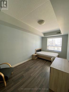 Waterloo condo for rent - A bedroom with a bed, chair, and window.