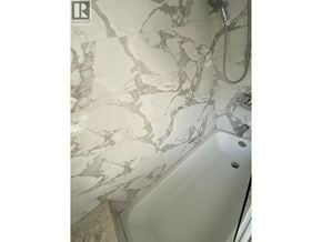 Vancouver apartment for rent - A white bathtub with a marble patterned wall behind it.
