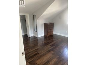 Vancouver apartment for rent - A room with wooden floors and a white wall with a mirror and a wooden chest of drawers.