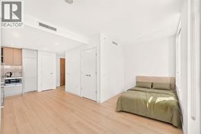 Burnaby apartment for rent - A bedroom with a bed, cupboard and a kitchen area.