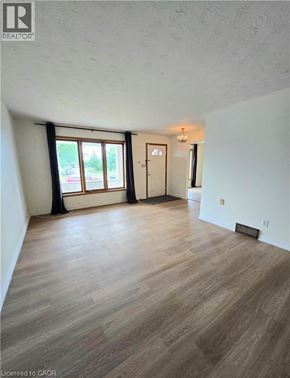 St. Catharines apartment for rent - A room with wooden flooring and a large window with black curtains.