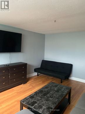 Ottawa triplex for rent - A living room with a black couch, a television, and a coffee table.