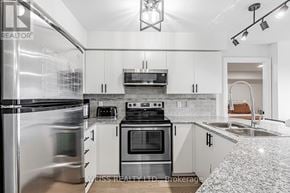 Toronto (Bathurst Manor) condo for rent - A modern kitchen with white cabinets and stainless steel appliances.