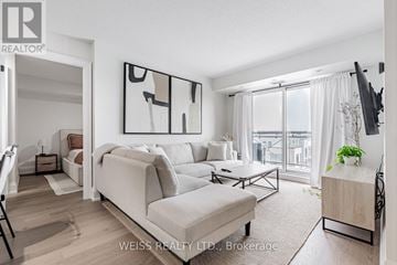 Toronto (Bathurst Manor) condo for rent - A living room with a large couch and a television on the wall.