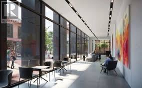Toronto (North St. James Town) condo for rent - A person is sitting on a chair in a brightly lit room with large windows.