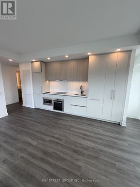 Toronto (North St. James Town) condo for rent - A spacious kitchen with white cabinets and a wooden floor.