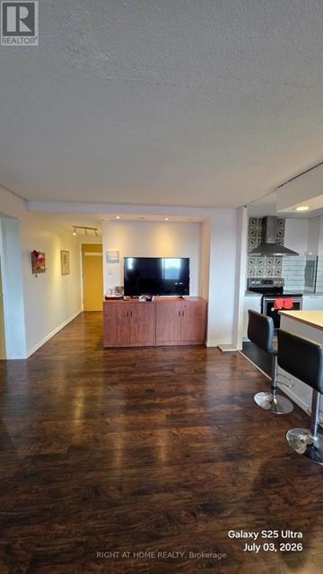 Toronto (Flemingdon Park) condo for rent - A living room with a wooden floor and a television on a wooden stand.