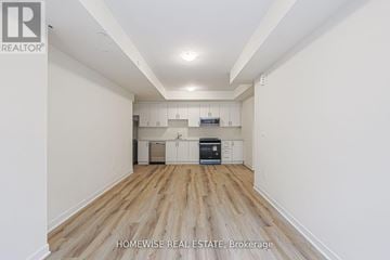 Pickering (Woodlands) townhouse for rent - A spacious room with wooden flooring and white walls, featuring a kitchen area with cabinets and a countertop.