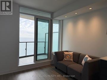 Toronto (South Parkdale) condo for rent - A living room with a grey couch and a window overlooking the ocean.