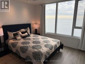 Toronto (South Parkdale) condo for rent - A bedroom with a large bed and a view of the ocean through the window.
