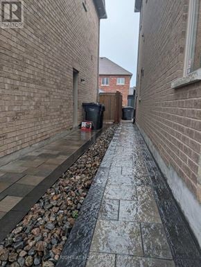 Brampton (Toronto Gore Rural Estate) apartment for rent - A narrow alley with a brick wall on one side and a gravel area on the other.