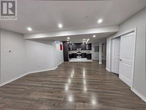 Brampton (Toronto Gore Rural Estate) apartment for rent - A spacious room with wooden flooring and a kitchen area in the background.