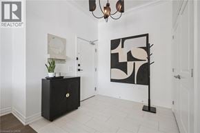 Guelph condo for rent - A black cabinet with a plant on top is in a room with a white wall and a painting.