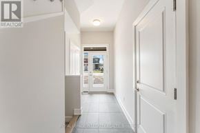 Ottawa townhouse for rent - A hallway with white walls and a tiled floor leading to a door with a view outside.