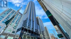 Toronto (North St. James Town) condo for rent - A tall building with a glass facade is the focal point of the image.