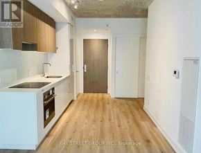 Toronto (Mount Pleasant West) condo for rent - A kitchen with wooden floors and white cabinets.