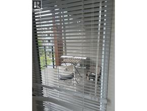Vancouver apartment for rent - A view through a window covered with white blinds.