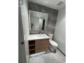 Richmond apartment for rent - A bathroom with a toilet, sink, and mirror.