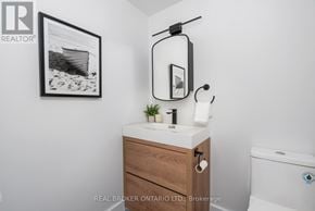 Toronto (Long Branch) condo for rent - A bathroom with a toilet, sink, and a picture hanging on the wall.