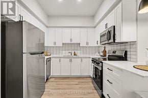 North Grenville apartment for rent - A kitchen with white cabinets and black appliances.