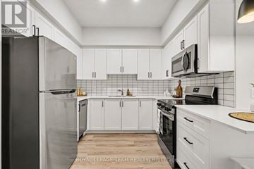 North Grenville apartment for rent - A kitchen with white cabinets and black appliances.