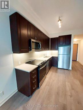 Toronto (Willowdale East) condo for rent - A kitchen with dark wood cabinets and stainless steel appliances.