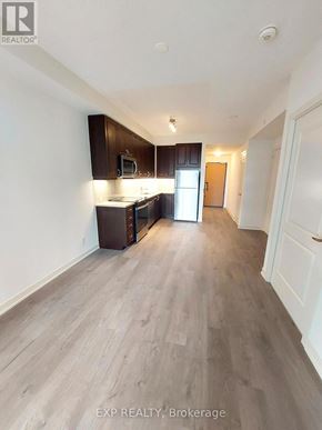 Toronto (Willowdale East) condo for rent - A kitchen with dark wood cabinets and a white refrigerator.