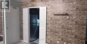 Toronto (Crescent Town) condo for rent - A brick wall with a white door and a small shelf above it.