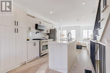 Barrie townhouse for rent - A modern kitchen with white cabinets and a central island.