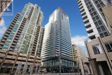 Toronto (Bay Street Corridor) condo for rent - A tall building with a glass facade stands in the middle of a city street.