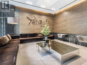 Toronto (Bay Street Corridor) condo for rent - A modern living room with a glass coffee table and a brown leather couch.
