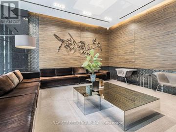 Toronto (Bay Street Corridor) condo for rent - A modern living room with a glass coffee table and a brown leather couch.