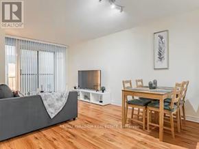 Toronto (Waterfront Communities) condo for rent - A living room with a grey couch, a wooden dining table with chairs, and a television on a stand.