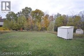 Kitchener townhouse for rent - A white shed sits in a grassy field with trees in the background.