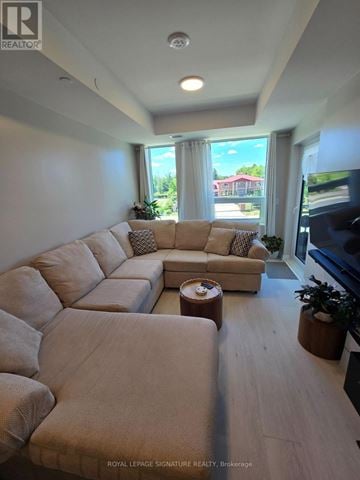 Oakville (Ga Glen Abbey) condo for rent - A living room with a large sectional sofa and a flat screen TV.