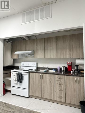 Cobourg condo for rent - A white stove with a black towel on it is in a kitchen.