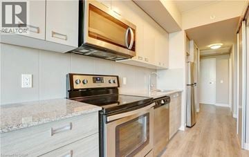 Waterloo condo for rent - A modern kitchen with a stove top oven and microwave above it.