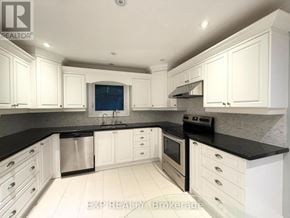 Whitchurch-Stouffville (Stouffville) apartment for rent - A kitchen with white cabinets and black countertops.