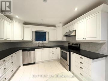 Whitchurch-Stouffville (Stouffville) apartment for rent - A kitchen with white cabinets and black countertops.