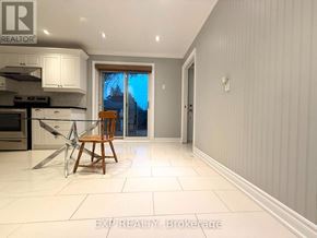 Whitchurch-Stouffville (Stouffville) apartment for rent - A kitchen with white cabinets and a wooden chair.