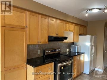 Ottawa townhouse for rent - A kitchen with wooden cabinets and black countertops.